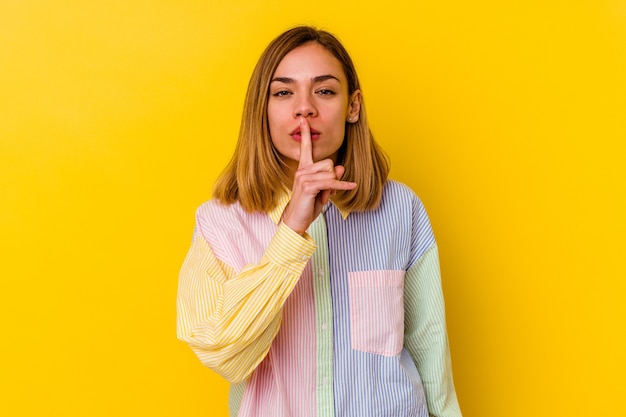 Jeune femme maigre caucasienne isolée sur un mur jaune gardant un secret ou demandant le silence.