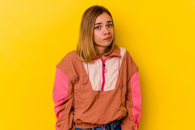 Jeune femme maigre caucasienne isolée sur mur jaune hausse les épaules et les yeux ouverts confus