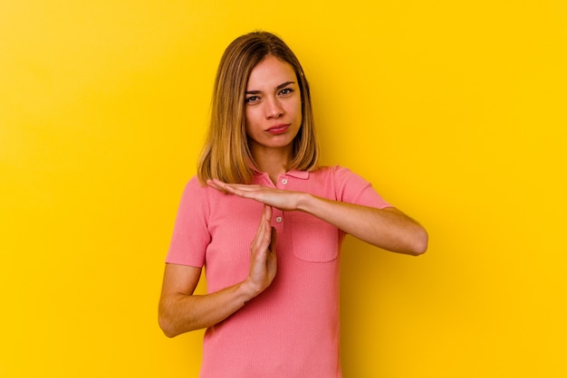 Jeune femme maigre caucasienne isolée sur un mur jaune montrant un geste de temporisation.