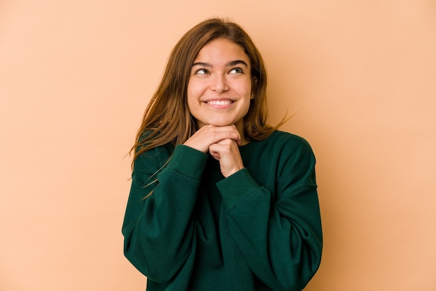 Jeune femme maigre caucasienne mains sous le menton, regarde joyeusement de côté.