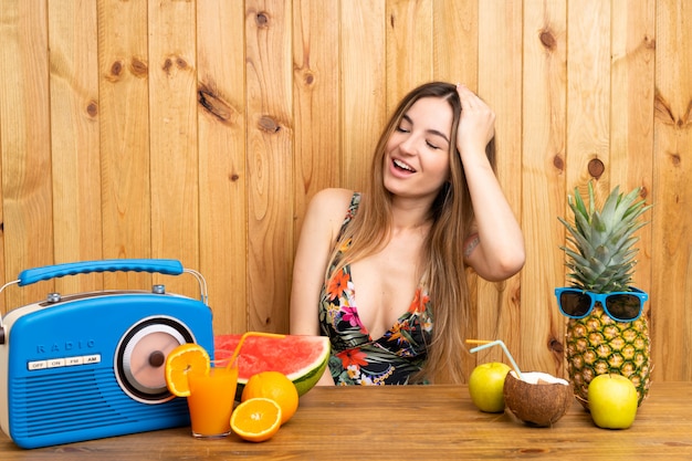 Jeune femme en maillot de bain avec beaucoup de fruits en riant