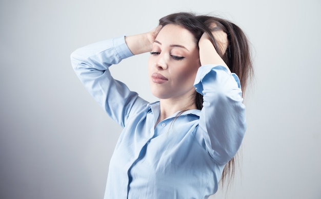 Jeune femme main dans les cheveux sur fond gris