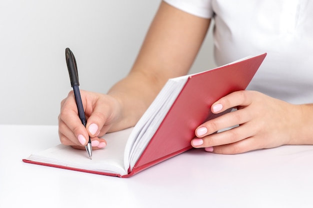 Jeune femme main écrit des notes à l'ordinateur portable la planification de son emploi du temps au tableau blanc