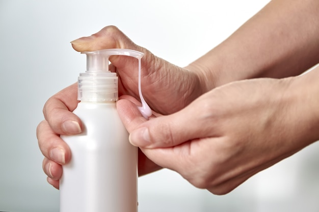 Une jeune femme mains en utilisant un désinfectant pour les mains ou du savon liquide. Prévention des maladies virales