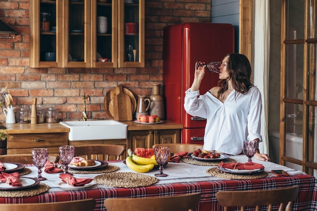 Jeune femme à la maison dans la cuisine buvant de l'eau du verre