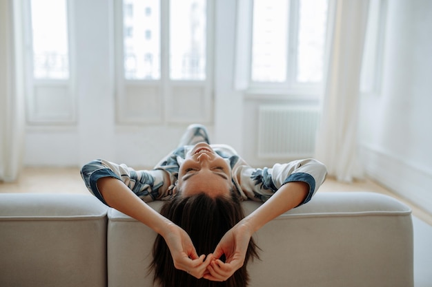 Jeune femme à la maison dans le salon se détendre sur le canapé