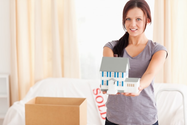 Jeune femme avec une maison modèle en regardant la caméra