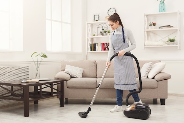 Jeune femme maison de nettoyage avec aspirateur