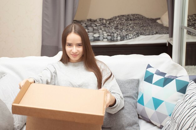 Une jeune femme à la maison ouvre une boîte à colis