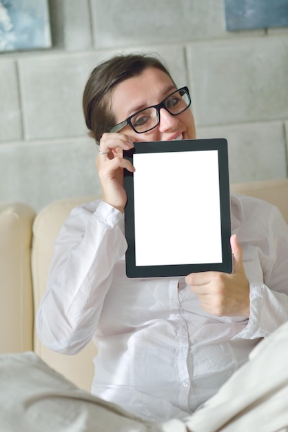 Jeune femme à la maison se détendre dans son salon en lisant une tablette numérique surfer sur Internet et travailler