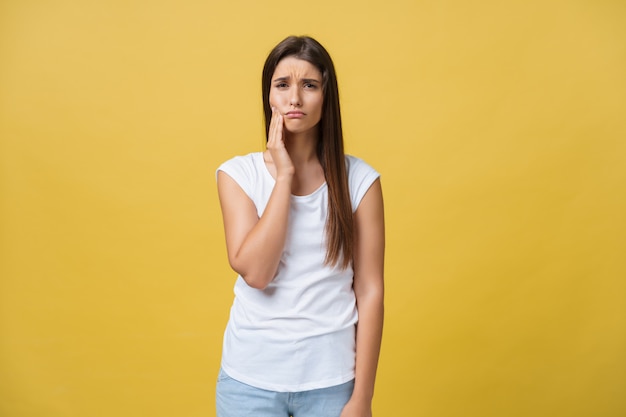 Jeune femme a un mal de dents, studio photo isolé sur fond jaune