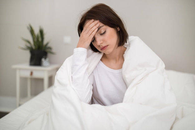 Jeune femme malade se réveillant avec des maux de tête le matin