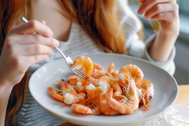 Une jeune femme mange des crevettes bouillies à la maison dans le concept de cuisine de manger des fruits de mer