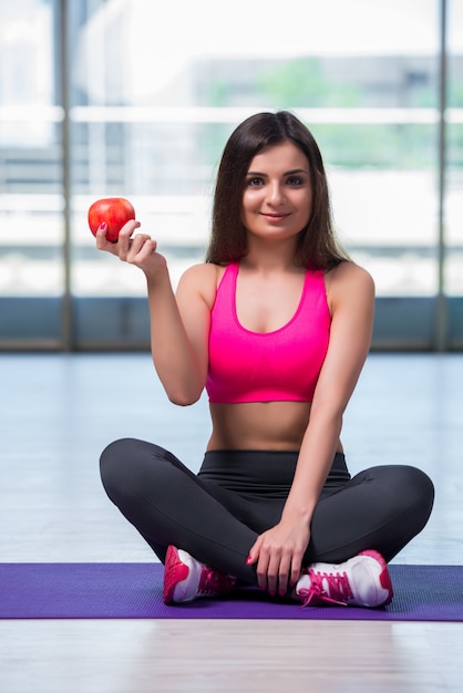 Jeune femme mange une pomme rouge dans le concept de santé