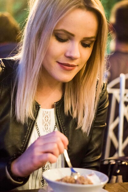 Photo une jeune femme mangeant de la crème glacée sur la table.