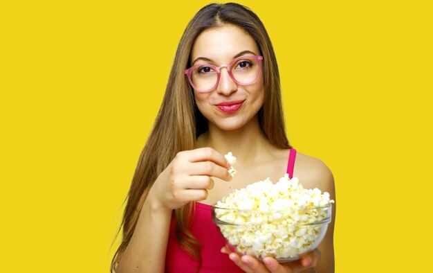 Photo une jeune femme mangeant du pop-corn sur un fond jaune