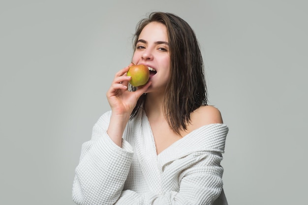 Jeune femme mangeant une pomme sur fond isolé gris fille mangeant un régime amaigrissant ou des soins dentaires