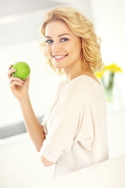 Jeune femme mangeant des pommes dans la cuisine