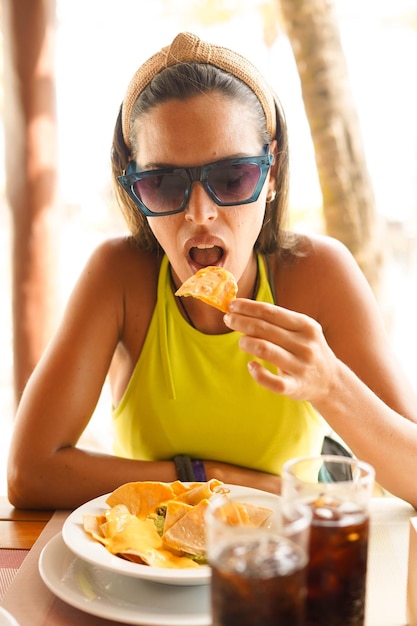 Une jeune femme mangeant une portion de nachos avec de la viande