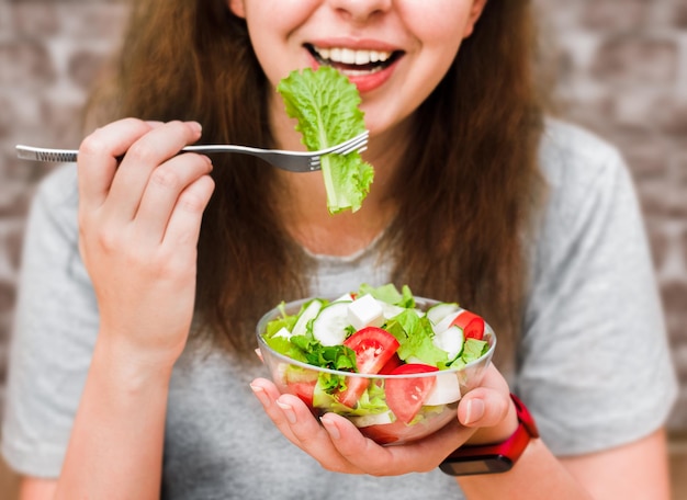 Jeune femme mangeant une salade de légumes frais