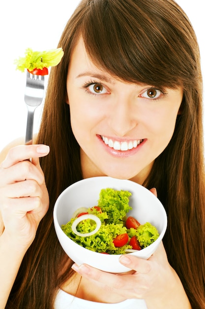 Une jeune femme mangeant une salade saine sur fond blanc