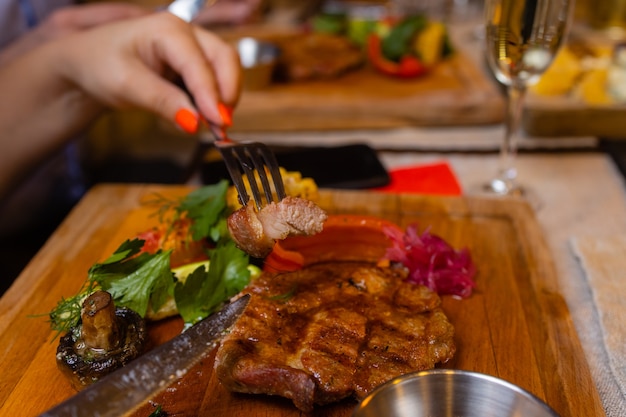 Jeune femme mangeant un steak grillé au restaurant