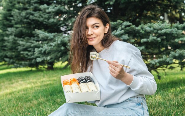 Une jeune femme mangeant des sushis dans le parc pique-nique dans la nature