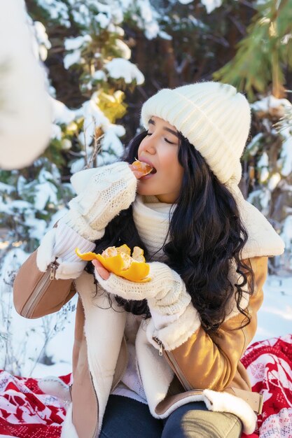 Jeune femme, manger, mandarine, dans, forêt hiver