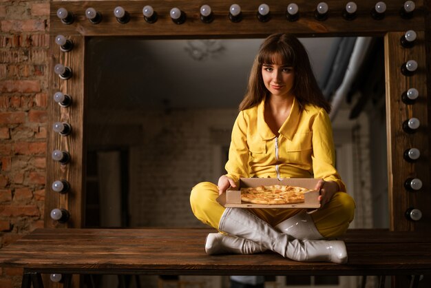 Jeune femme, manger, pizza, séance, dans, a, kombineh jaune
