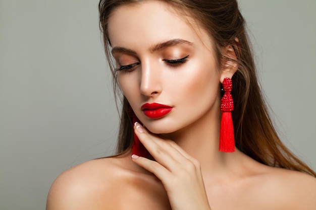 Jeune femme mannequin avec maquillage d'événement et boucles d'oreilles bijoux sur fond