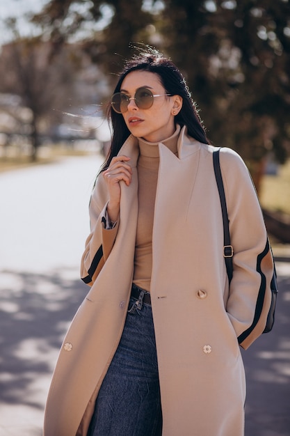 Jeune femme en manteau beige marchant dans la rue