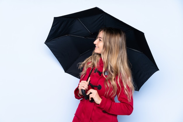 Jeune femme avec manteau d'hiver et tenant un parapluie avec une expression heureuse