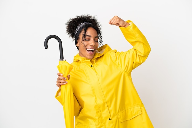 Jeune femme avec manteau imperméable et parapluie isolé sur fond blanc célébrant une victoire