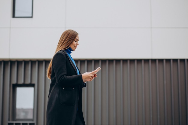 Jeune femme en manteau noir à l'aide de téléphone