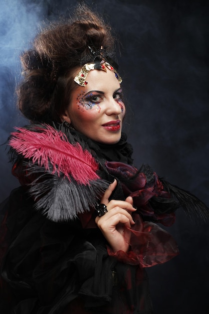 Jeune femme avec maquillage créatif et coiffure posant sur fond sombre Fête et halloween