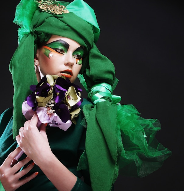 Jeune femme avec maquillage créatif tenant un bouquet de bijoux