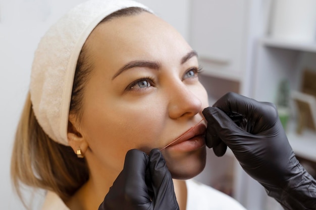 Jeune femme avec un maquillage permanent sur ses lèvres dans un salon de cosmétologues tirage de tatouage de maquillage permanent