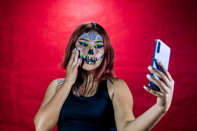 Une jeune femme maquillée pour la fête d'halloween prend un selfie depuis son téléphone portable