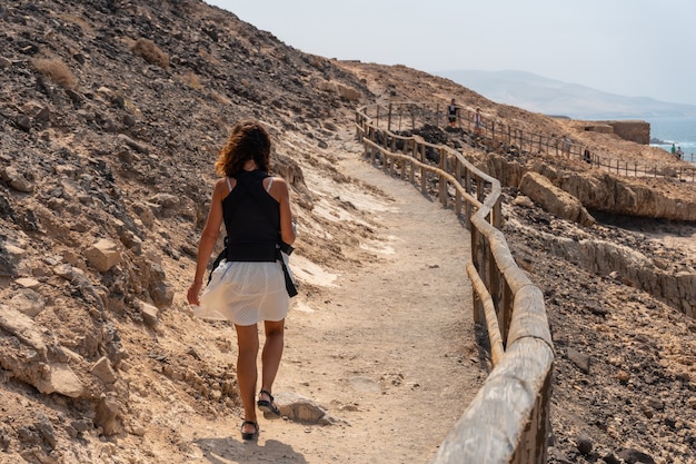 Une jeune femme marchant sur le chemin dans les Cuevas de Ajuy, Pajara, côte ouest de l'île de Fuerteventura, Îles Canaries. Espagne