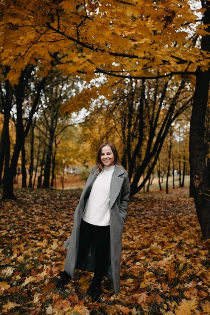 Jeune femme marchant dans le parc d'automne dans un long manteau