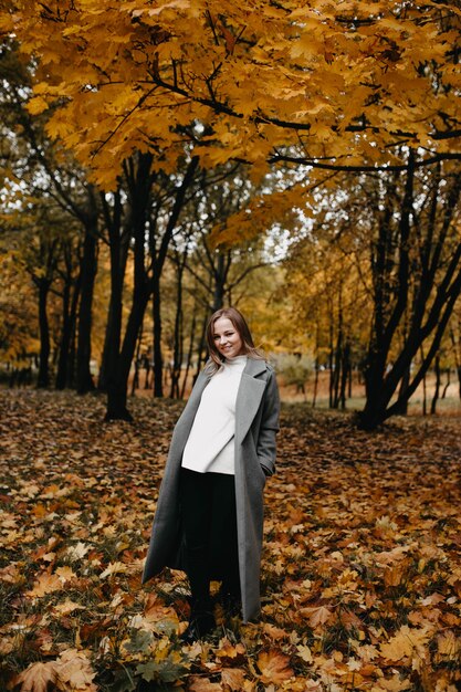 Jeune femme marchant dans le parc d'automne dans un long manteau