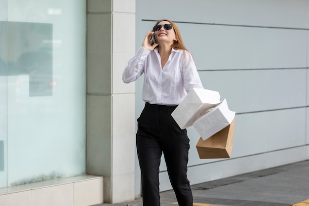 Jeune femme marchant dans la rue portant ses sacs de l'offre shopping qu'elle a faite au centre commercial