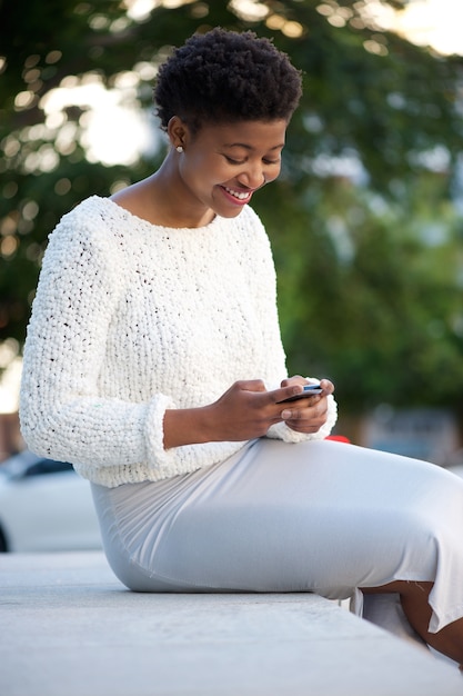 Photo jeune femme marchant et envoi de sms sur téléphone portable