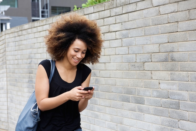 Jeune femme marchant et envoyant un message texte