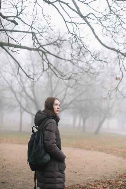 Jeune femme marchant le matin brumeux dans la forêt d'automne ou le parc seul