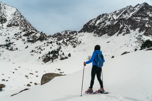 Jeune femme marchant avec des raquettes à neige en haute montagne