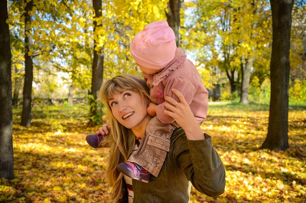Jeune femme marchant avec son petit enfant dans le parc d'automne lumineux