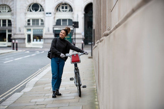 Photo jeune femme marchant avec son vélo dans la ville