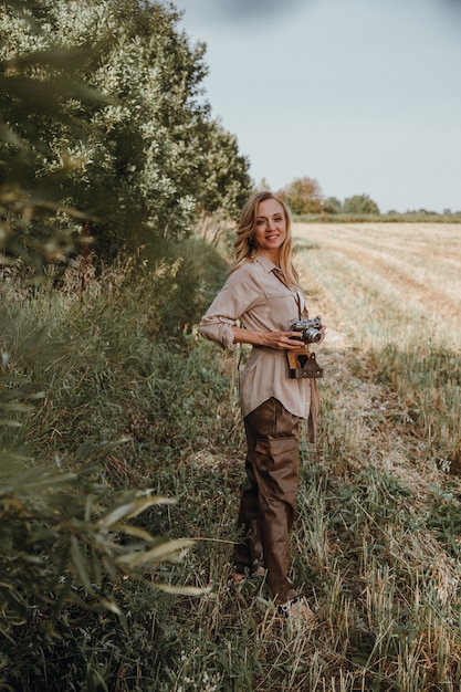 Une jeune femme marche avec un appareil photo rétro et prend des photos de la nature