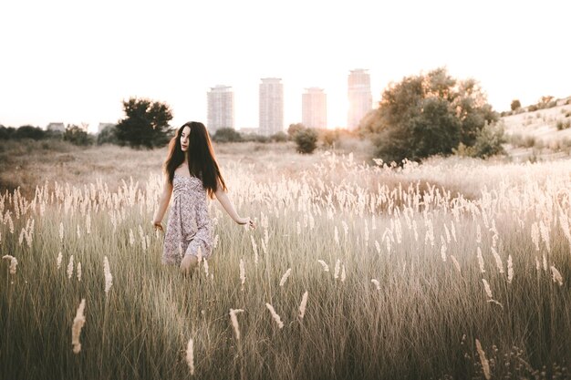 Photo une jeune femme marche au milieu des plantes sur le champ.